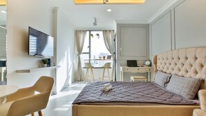 Ett modernt hotellrum med en säng, ett skrivbord, en stol och en tv.