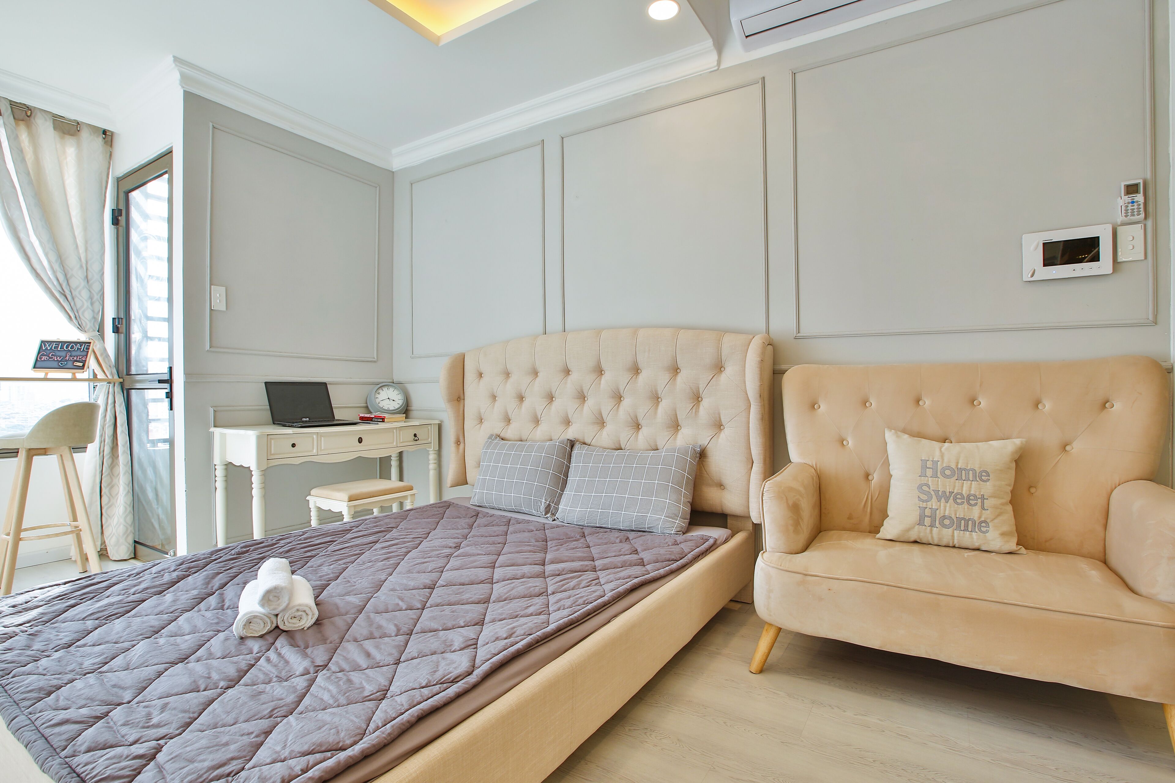 A bedroom with a bed, a sofa, a desk, and a computer.