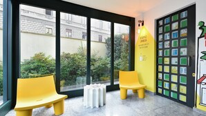 A modern interior with large windows, yellow seating, and a wall with colorful illustrations. - Residence Cimarosa (Milan)