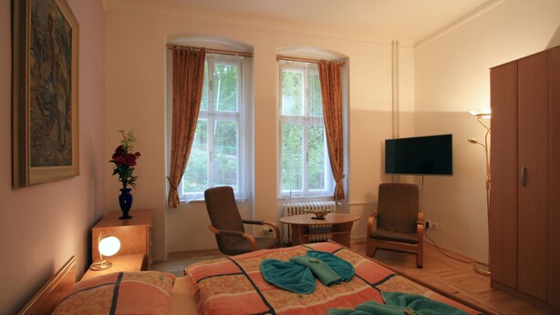Quarto de hotel com duas camas, televisão, escrivaninha e uma cadeira.