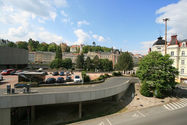 A parking area with cars, a pedestrian crossing, and a building with a dome and red roof.