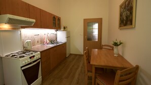 Uma cozinha com armários de madeira, fogão, geladeira e uma mesa de jantar com cadeiras.