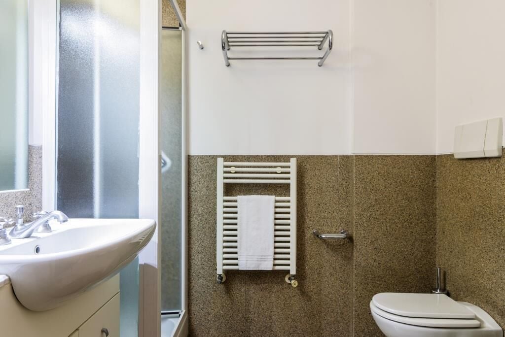 A bathroom with a sink, toilet, and towel rack.