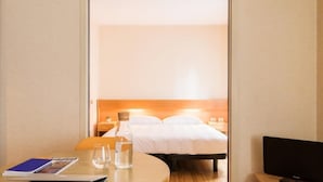 A hotel room with a bed, a desk with a laptop, a glass of water, and a television. - Residence Portello (Milan)