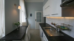 A modern kitchen with a dark countertop, white cabinets, and a stainless steel sink. - Apartment No. 4B I. P. Pavlova 32 (Karlovy Vary)