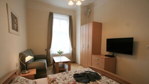 A hotel room with two beds, a desk, a television, a wardrobe, and a window with curtains. - Apartment No. 4B I. P. Pavlova 32 (Karlovy Vary)