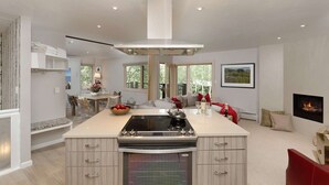 Una cocina moderna con una isla central, horno empotrado y un área de comedor con vistas al exterior.