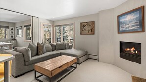 Una sala de estar moderna con un sofá seccional gris, una mesa de centro de madera y una chimenea.