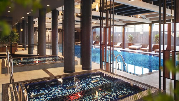 A modern indoor pool area with multiple pools, large pillars, and lounge chairs. - Radisson Blu Hotel Sopot (Sopot)