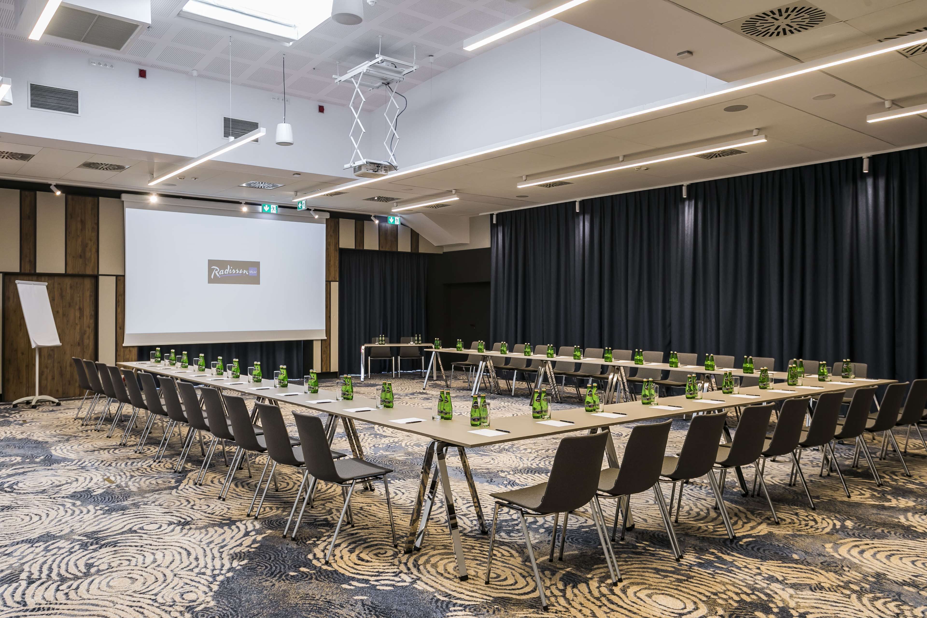 A conference room with a long table, chairs, and a projector screen.