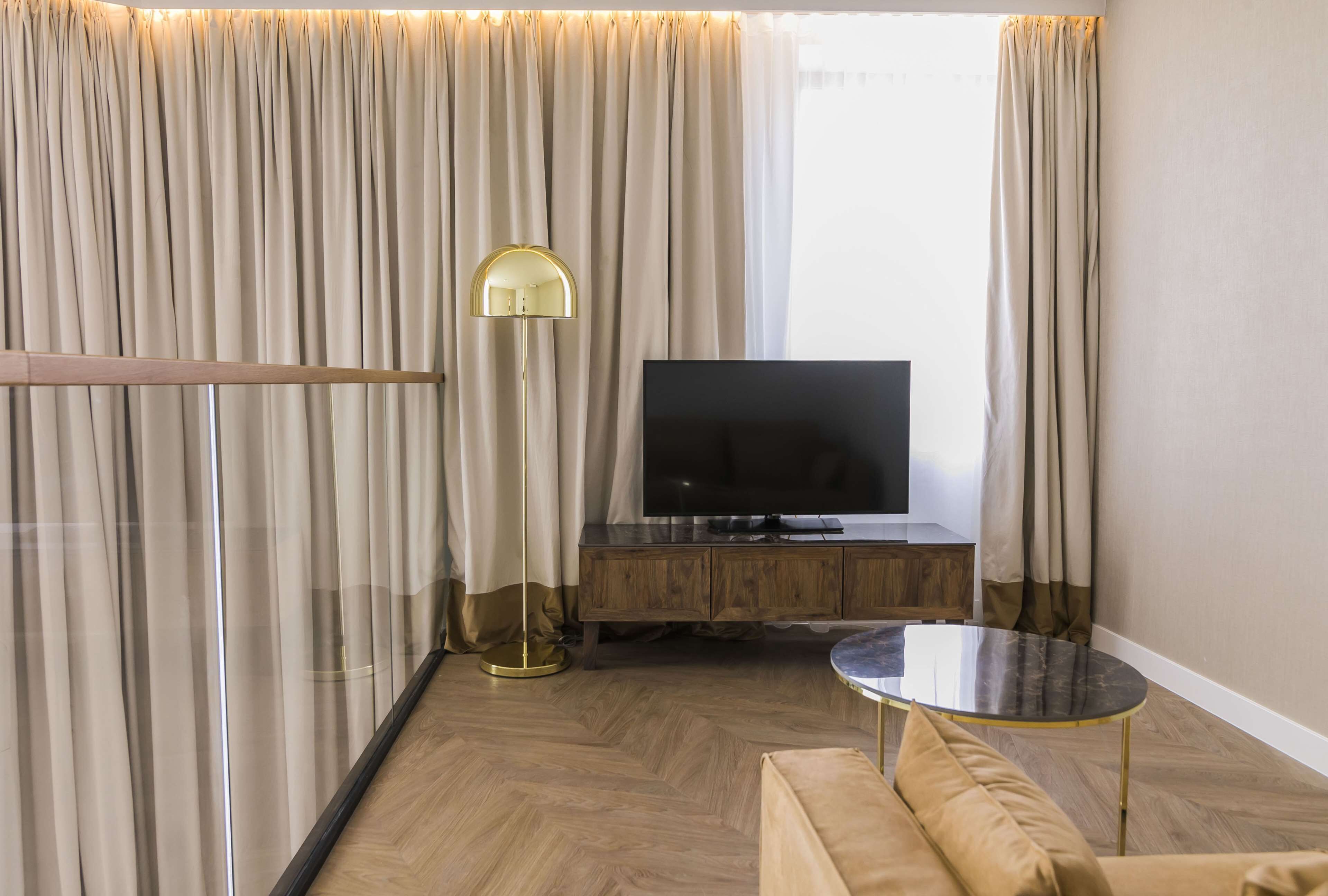 Een moderne woonkamer met een flatscreen televisie, een ronde salontafel, een bank en een vloerlamp.