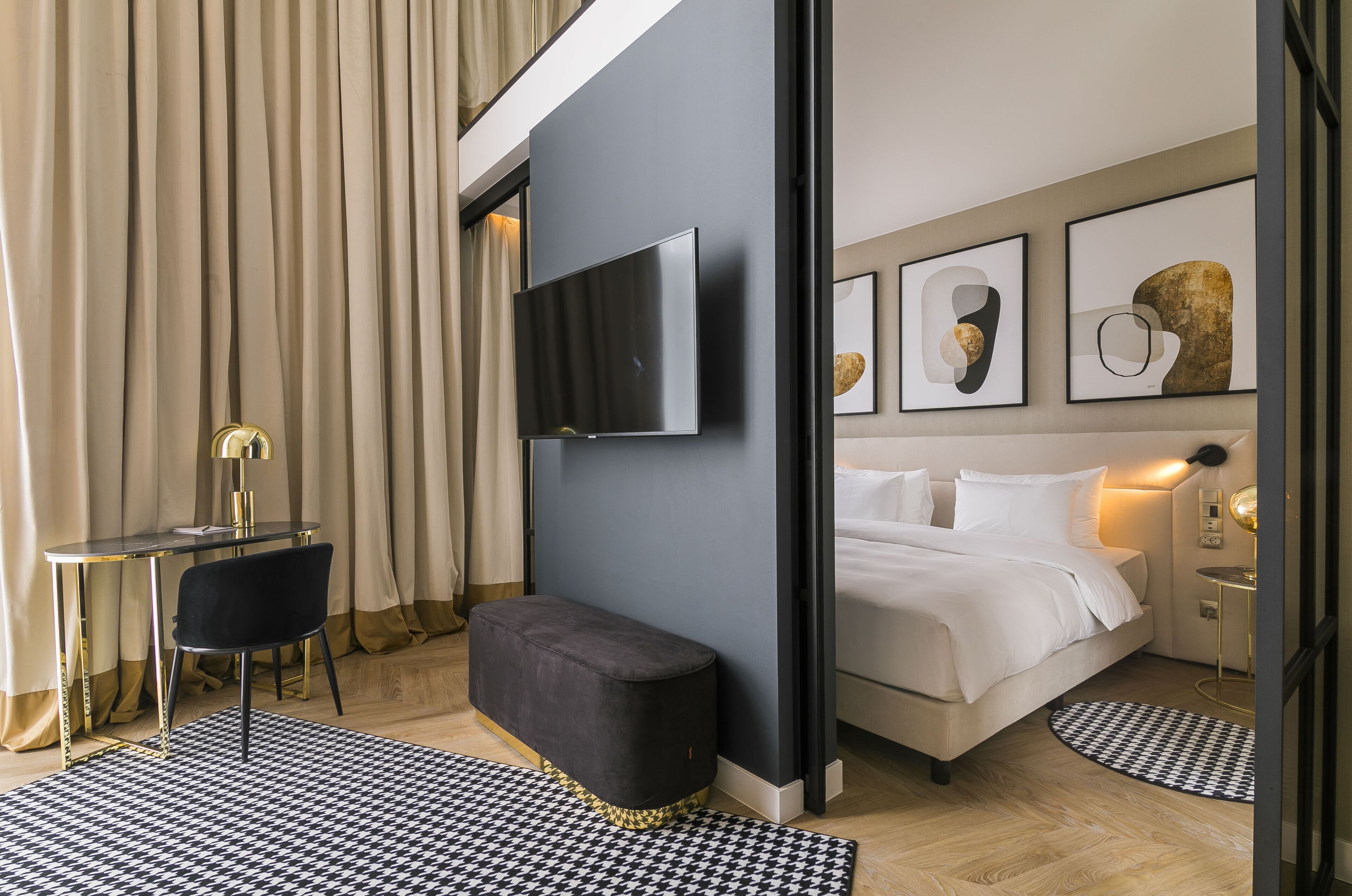 Ein modernes Hotelzimmer mit einem Bett, einem Schreibtisch, einem Stuhl und einem an der Wand befestigten Fernseher.
