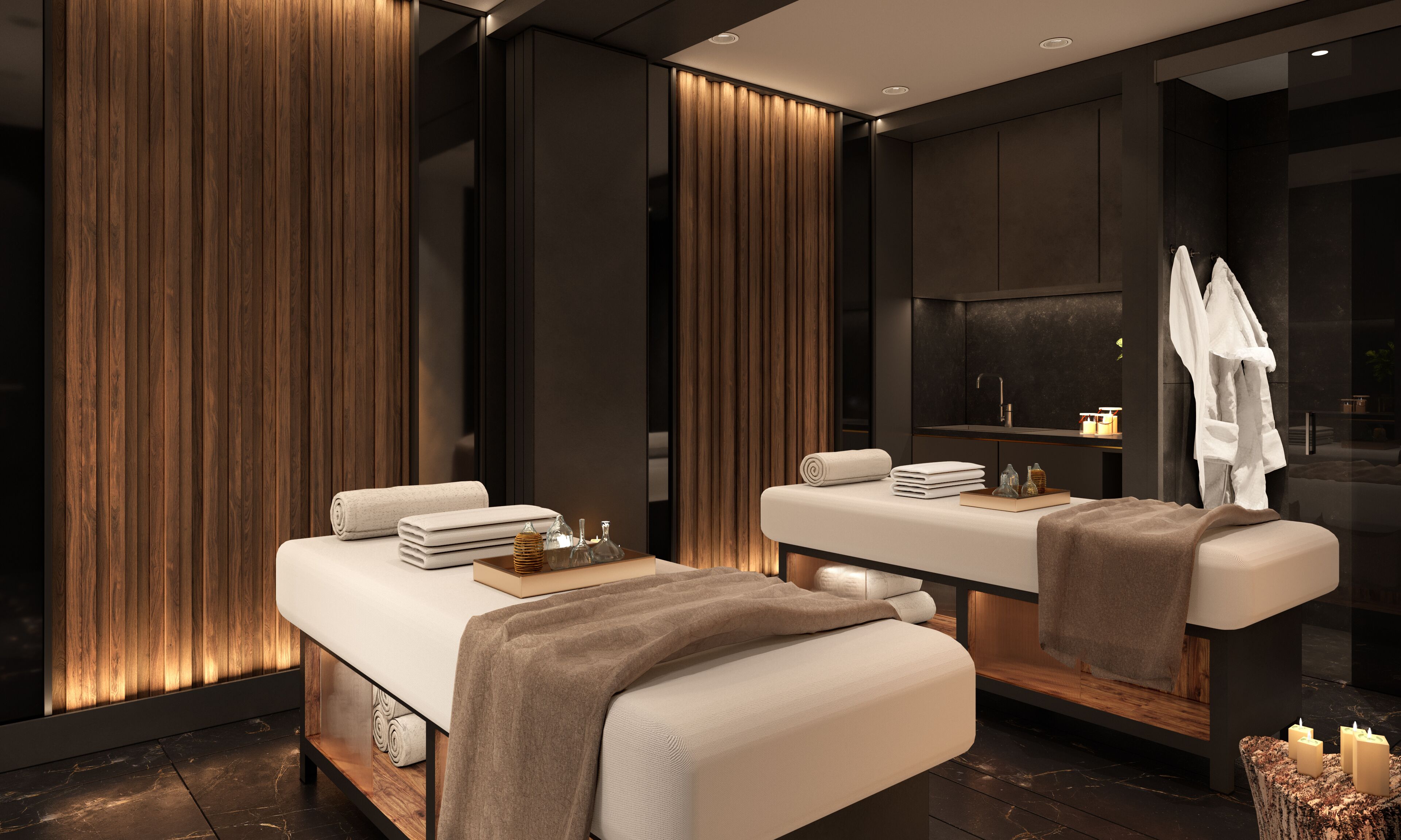 A modern spa room with two treatment tables, wooden paneling, and a dark-toned reception area.