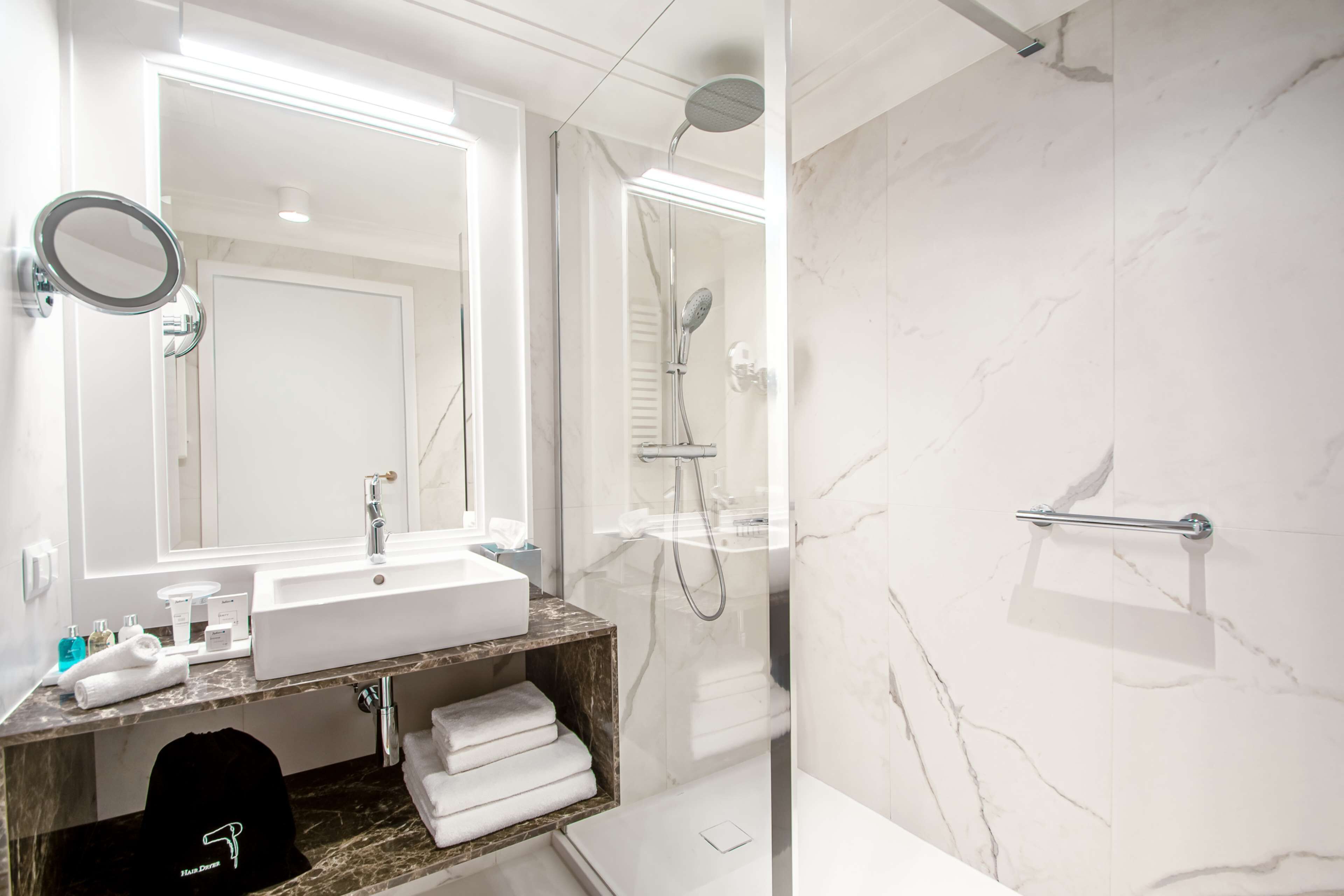 Een moderne badkamer met een grote spiegel, een wastafel en een douche.