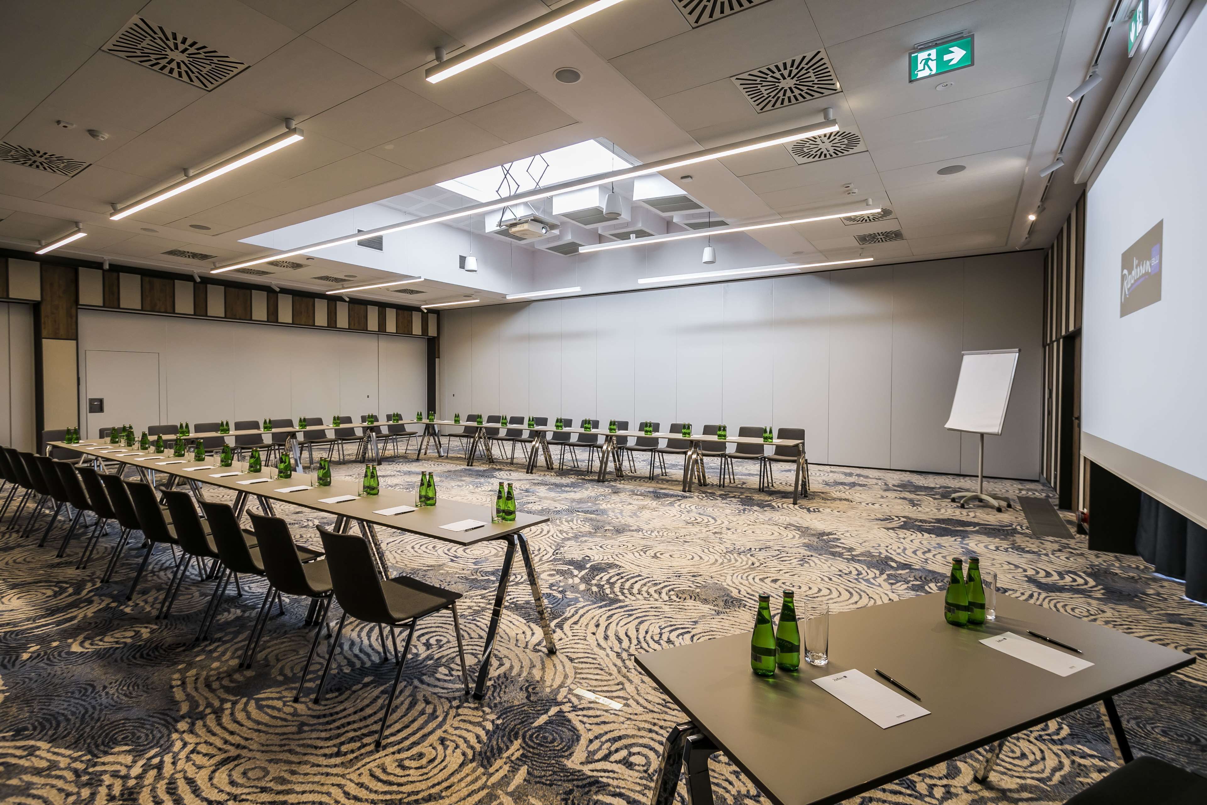 Un salón de conferencias con una mesa larga, sillas y una pizarra.