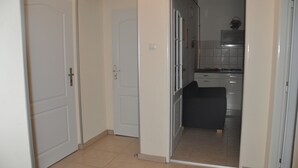 A hallway leading to a kitchen with white doors and tiled flooring. - Apartment No. 40 Stará Louka 20 (Karlovy Vary)