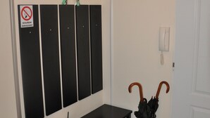 A hallway with a coat rack, a no smoking sign, a desk with a laptop, a black umbrella, and a door. - Apartment No. 40 Stará Louka 20 (Karlovy Vary)