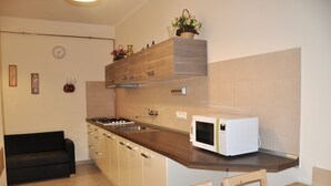 A modern kitchen with a wooden countertop, a built-in microwave, a sink, and a black sofa. - Apartment No. 40 Stará Louka 20 (Karlovy Vary)