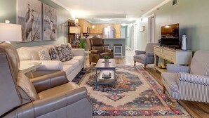 Una sala de estar con sofá, sillones, una mesa de centro y una alfombra estampada.