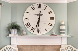 A large wall-mounted clock with Roman numerals and the text "Paris Standard Clock Company" on a light blue wall.