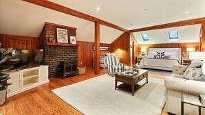 Un salón amplio con chimenea, una cama grande y un techo alto con tragaluces.