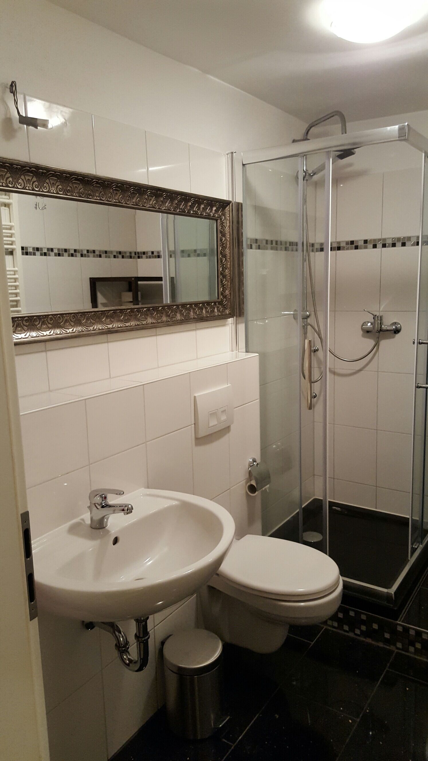 A bathroom with a white sink, toilet, and a glass-enclosed shower.
