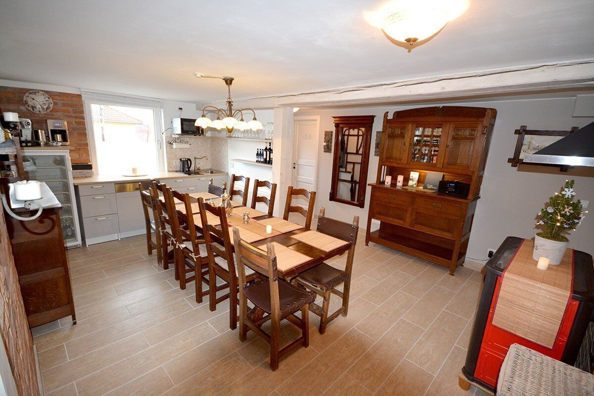 A compact kitchen with a dining area, featuring a wooden table and chairs, a built-in oven, and a small refrigerator.