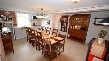 A compact kitchen with a dining area, featuring a wooden table and chairs, a built-in oven, and a small refrigerator.