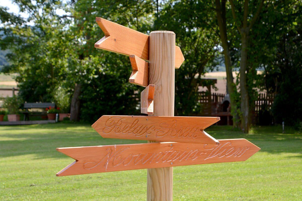 A wooden directional signpost with arrows pointing to 'Relax Beach' and 'Mountains View'.