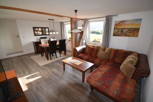 Una sala de estar con piso de madera, un sofá, una mesa de centro y un comedor con sillas y una mesa.