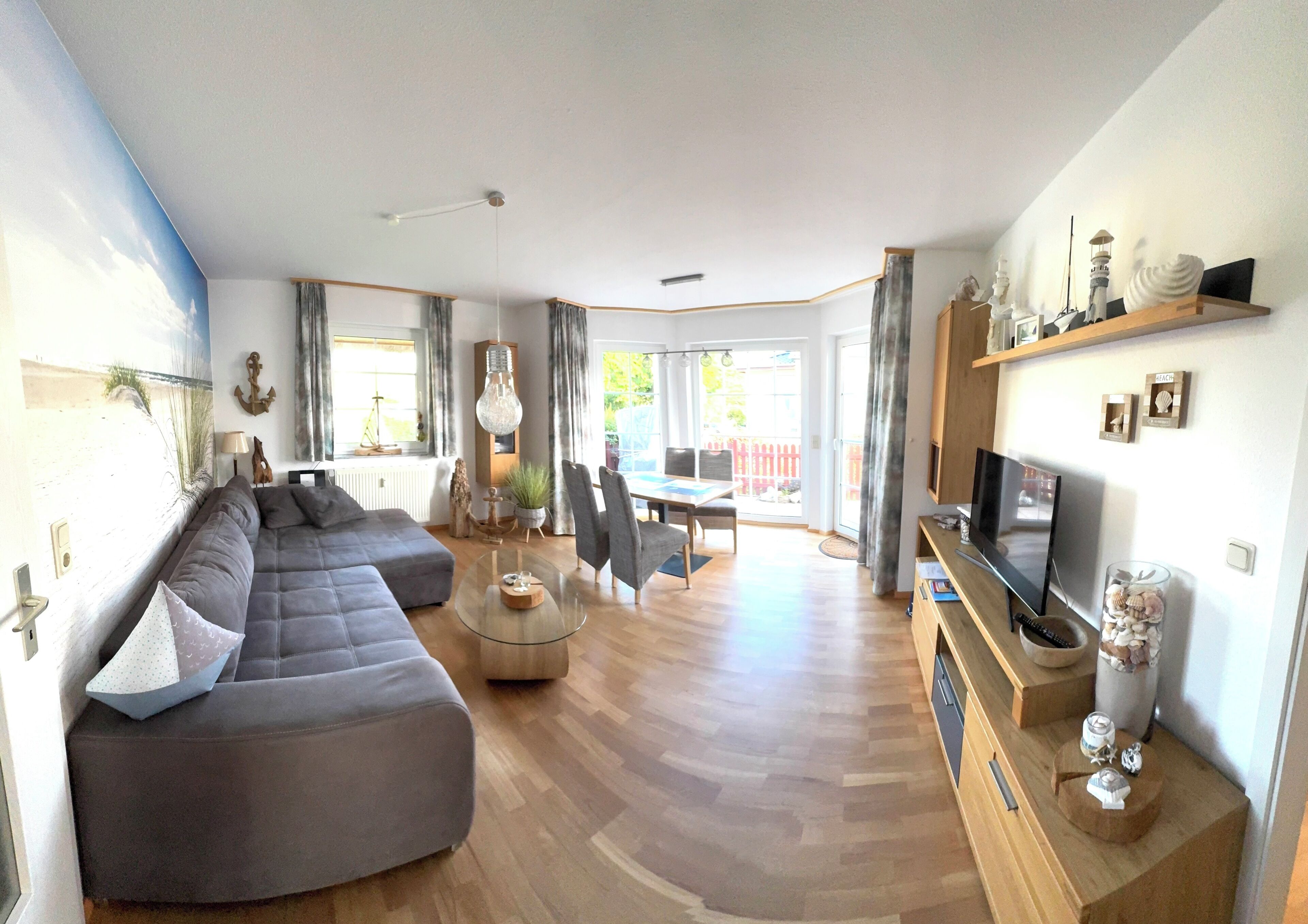 A modern living room with a sectional sofa, a glass coffee table, and a TV on a wooden stand.