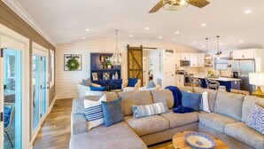 A spacious living room with a large sectional sofa, a ceiling fan, and a kitchen in the background. - Summer STATus w/Optional Boat Rental (Mooresville)