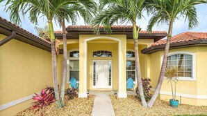 A two-story house with a yellow facade, a tiled roof, and a central entrance with a white door. - Paradise Palms - Luxury Home - Bikes & Kayaks (Cape Coral)