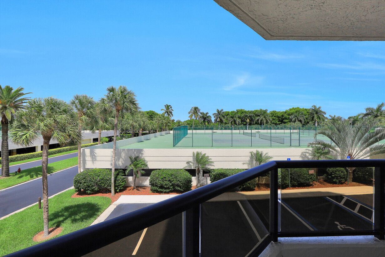 Una cancha de tenis rodeada de palmeras y una carretera.