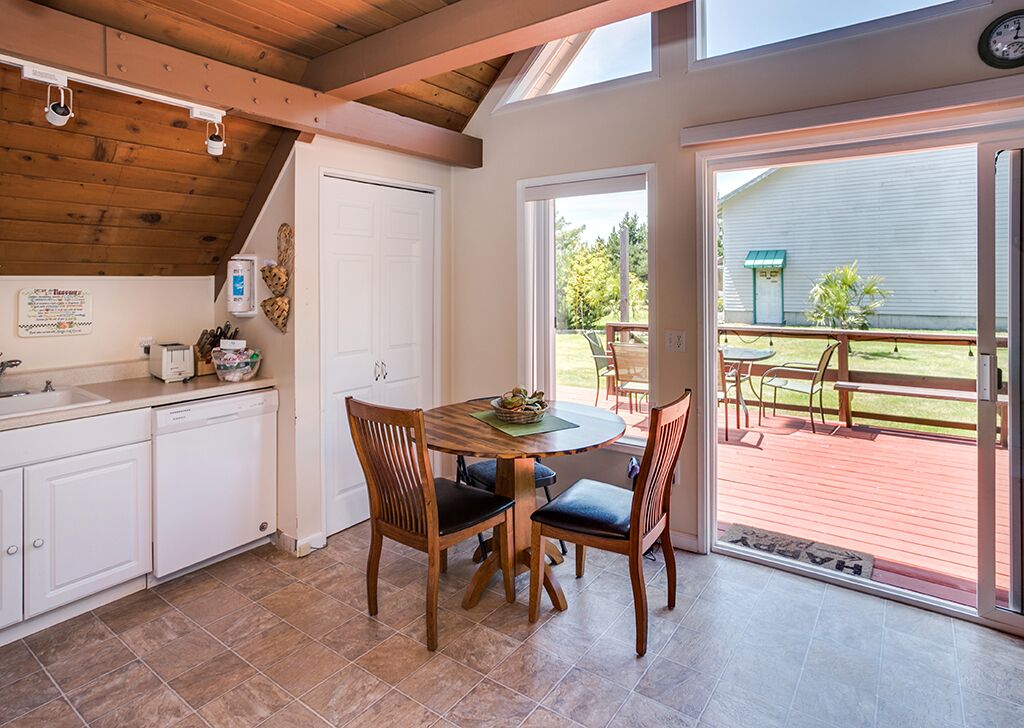 Une cuisine avec un coin repas, un plafond en bois et une vue sur le jardin arrière.