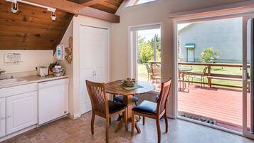 Une cuisine avec un coin repas, un plafond en bois et une vue sur le jardin arrière.