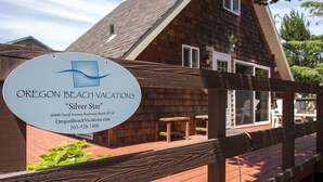 A wooden deck with a sign for Oregon Beach Vacations "Silver Star" at 26440 David Avenue, Rockaway Beach, 97140. - Romantic A-Frame Beach Cottage, Blocks to the Beach, Deck, Fireplace and Firepit (Rockaway Beach)