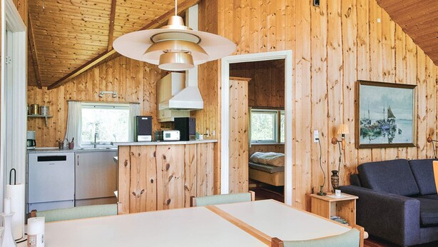 A wooden interior with a dining area, kitchen, and a bed in a loft-style room. - 6 Person Holiday Home in Vig (Vig)