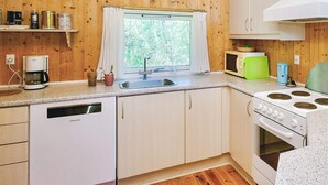 A compact kitchen with wooden walls, a window with curtains, a sink, a coffee maker, a microwave, and a stove. - 6 Person Holiday Home in Vig (Vig)