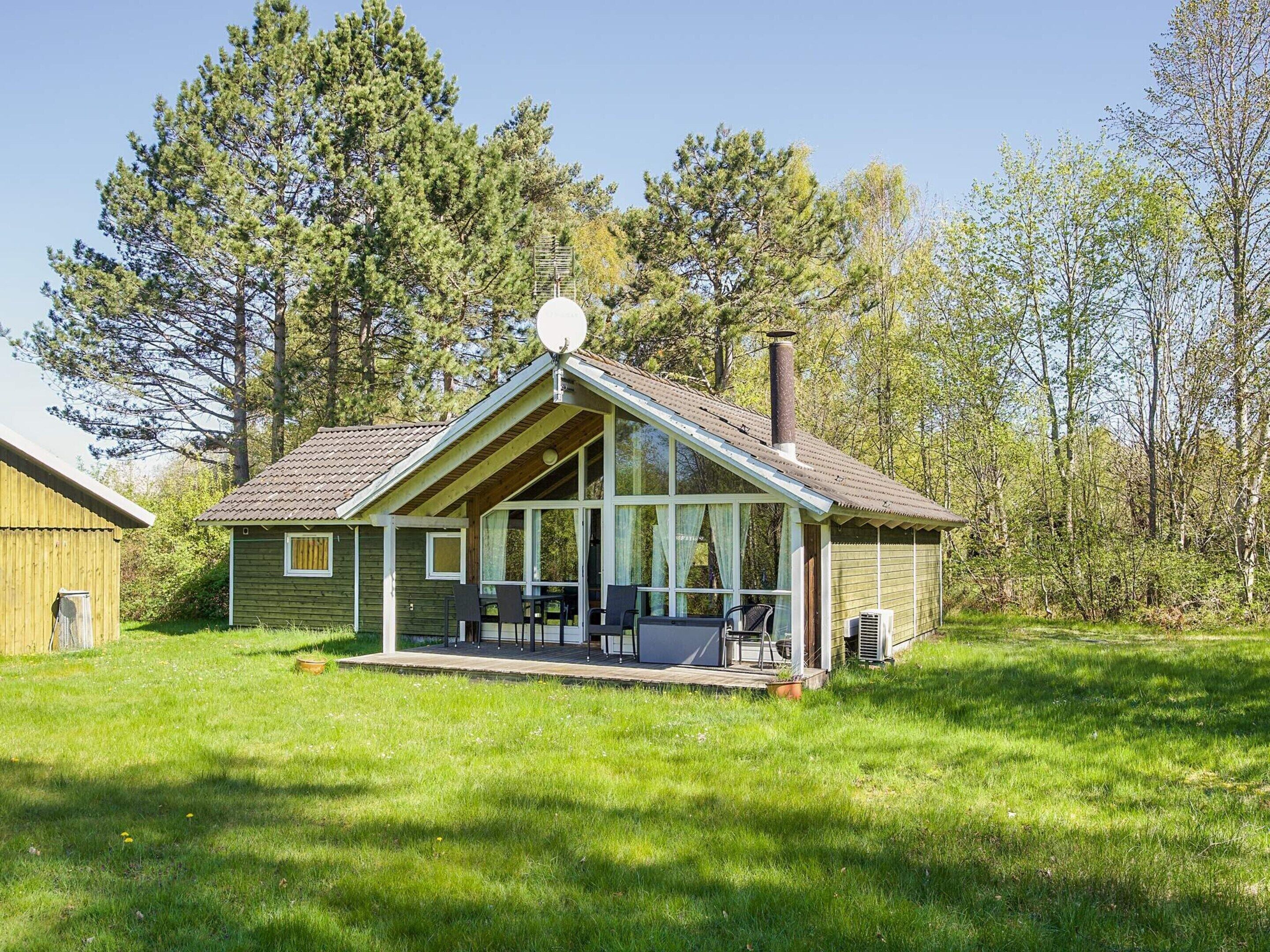 A single-story wooden cabin with a sloped roof, large windows, and a chimney.