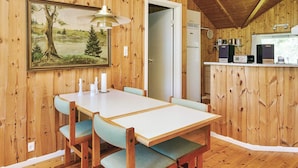 A wooden interior with a dining table, chairs, a painting, a kitchen area, and a door leading to another room. - 6 Person Holiday Home in Vig (Vig)