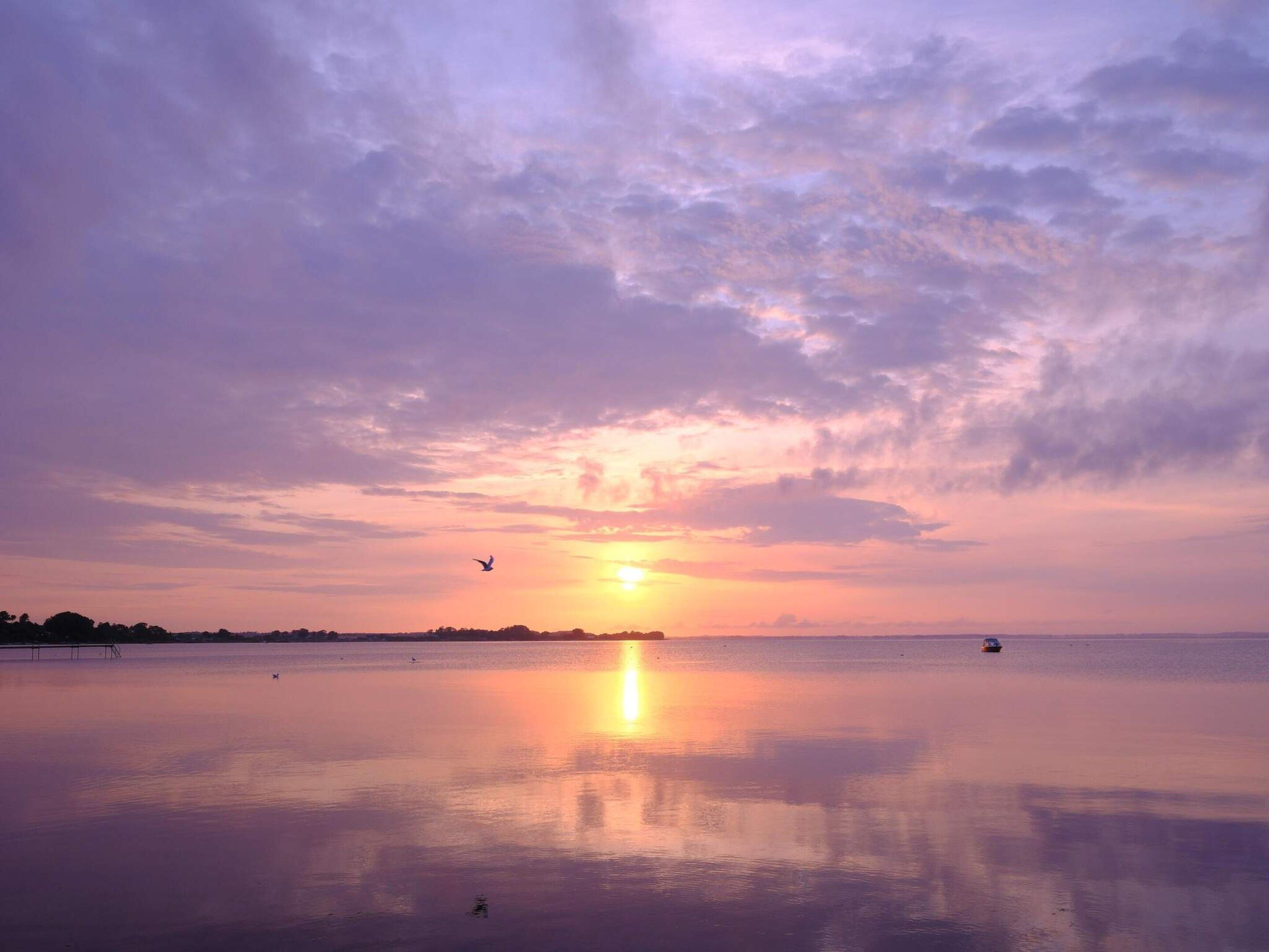 A calm body of water reflecting the sky during sunset.