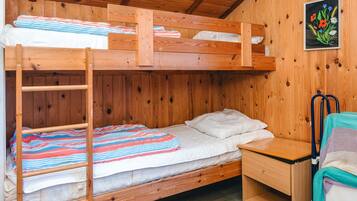 Quarto com beliche, uma escada de madeira, uma pequena escrivaninha e uma cadeira.