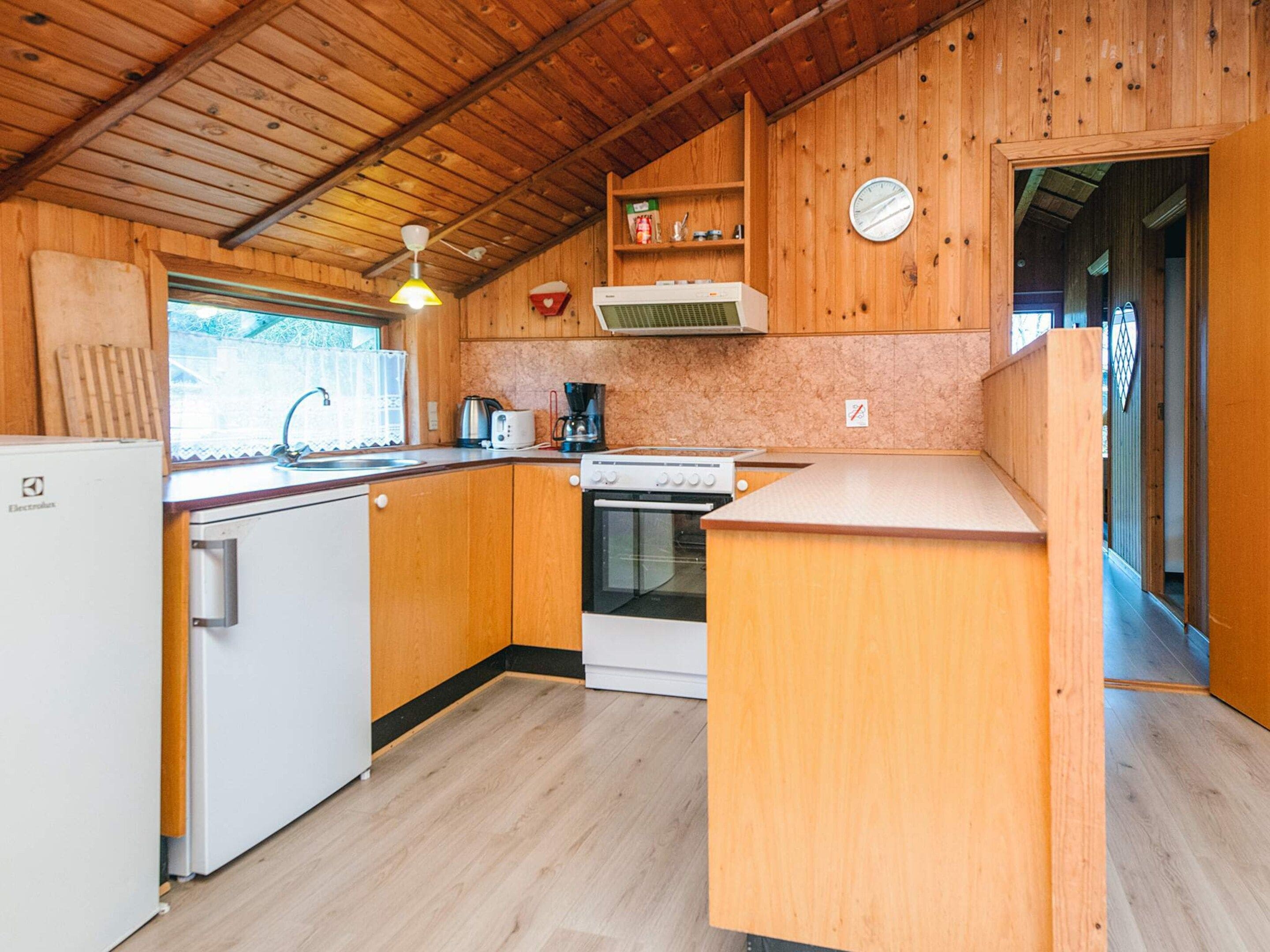 A compact kitchen with wooden cabinets, a built-in oven, a coffee maker, and a refrigerator.