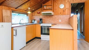 A compact kitchen with wooden cabinets, a built-in oven, a coffee maker, and a refrigerator.