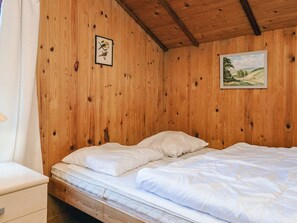 A wooden room with a bed, a nightstand, and two framed pictures on the wall. - 6 Person Holiday Home in Bjert (Bjert)