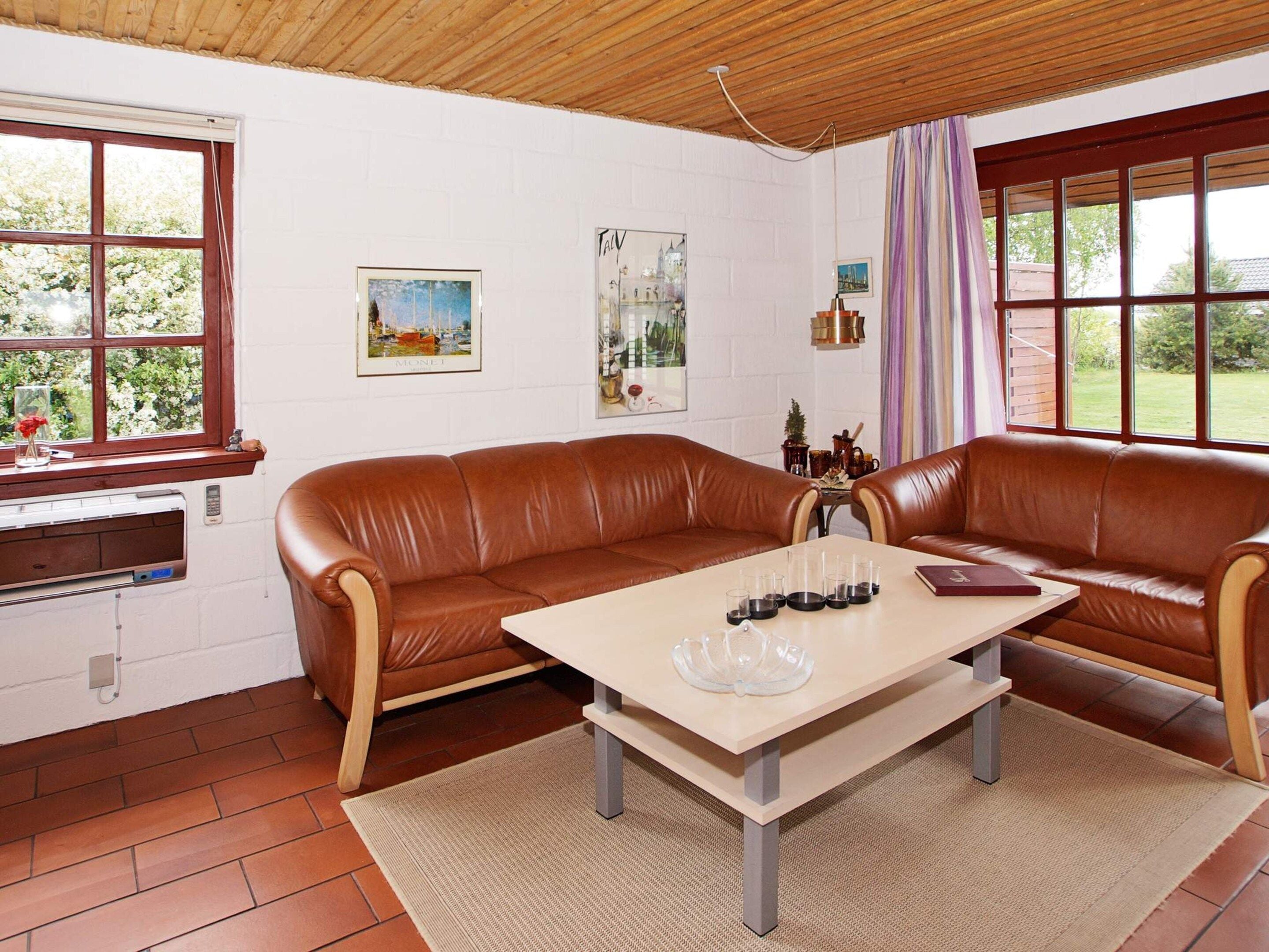 Une pièce avec un canapé en cuir marron, une table en bois sur laquelle se trouve du matériel de laboratoire, et une fenêtre donnant sur un paysage verdoyant.