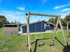 Relax in a serene backyard with a charming swing set and patio area.