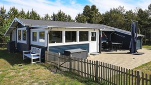 Un petit bâtiment d’un seul étage, doté d’un patio couvert, d’un banc et d’un espace extérieur clôturé.