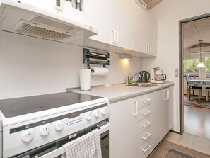Une cuisine moderne avec des meubles blancs, une cuisinière encastrée et une machine à café.